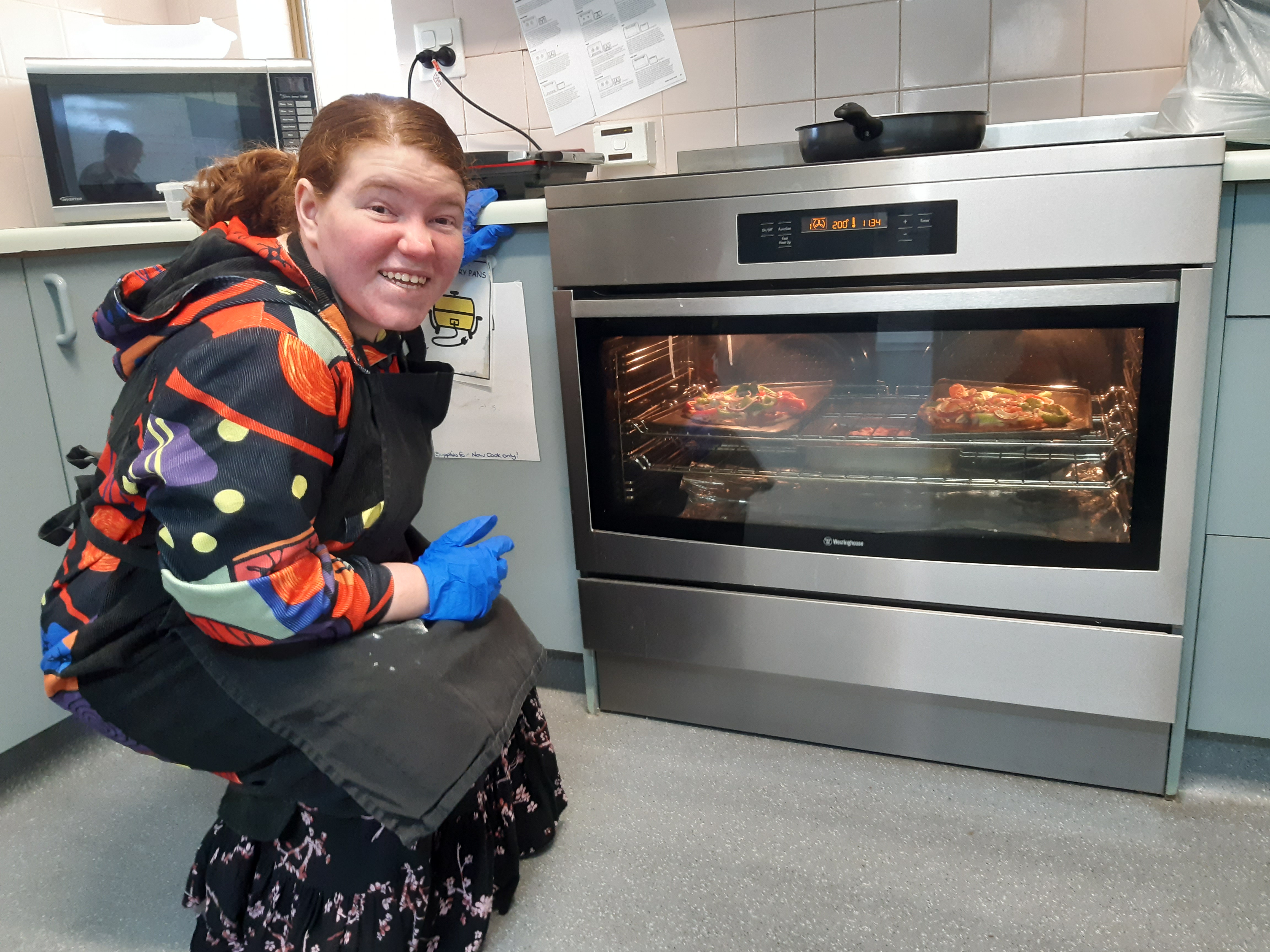 a woman cooks pizza in oven at Group Supports Cooking Program at Distinctive Options Noweyung