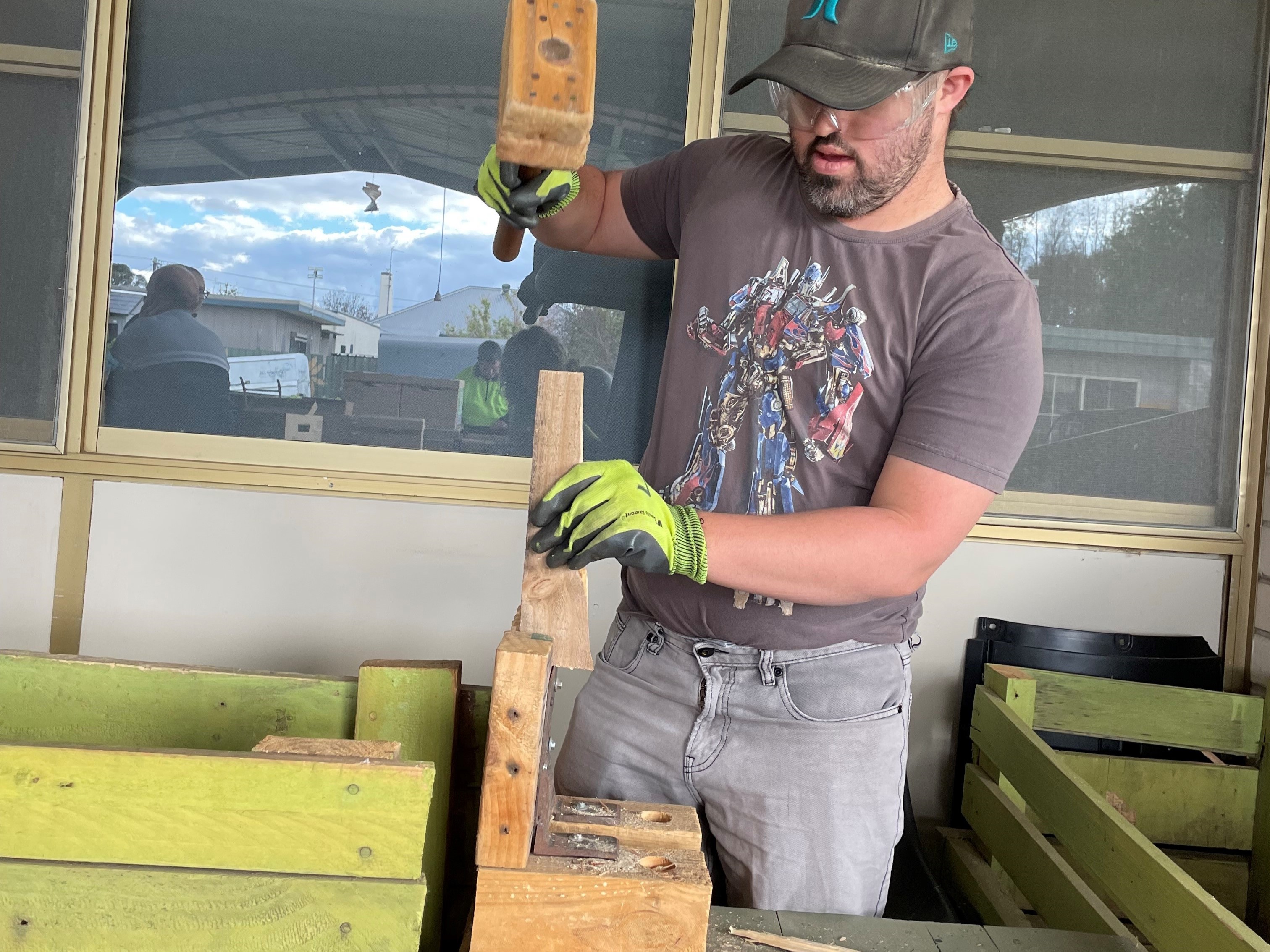 A man in safety gear spliting wood at Group Supports IT and Photography at Distinctive Options Noweyung