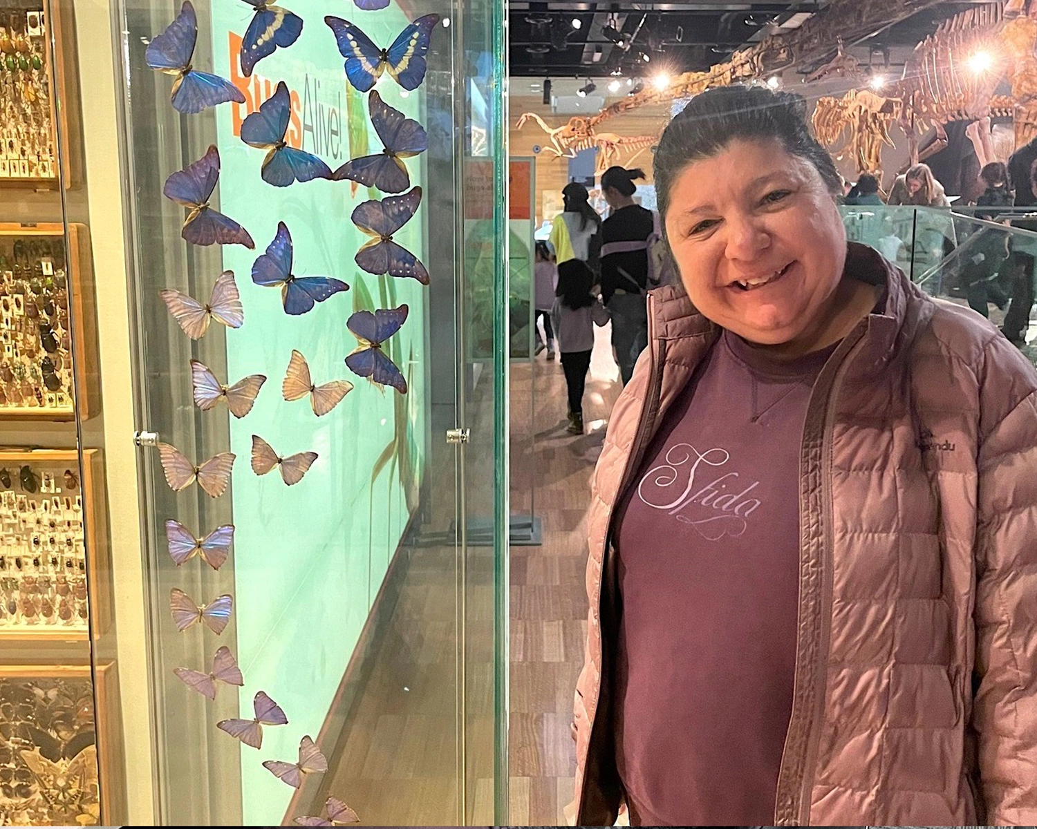 A woman smiles while looking at at butterfly collection in a museum with independent living supports