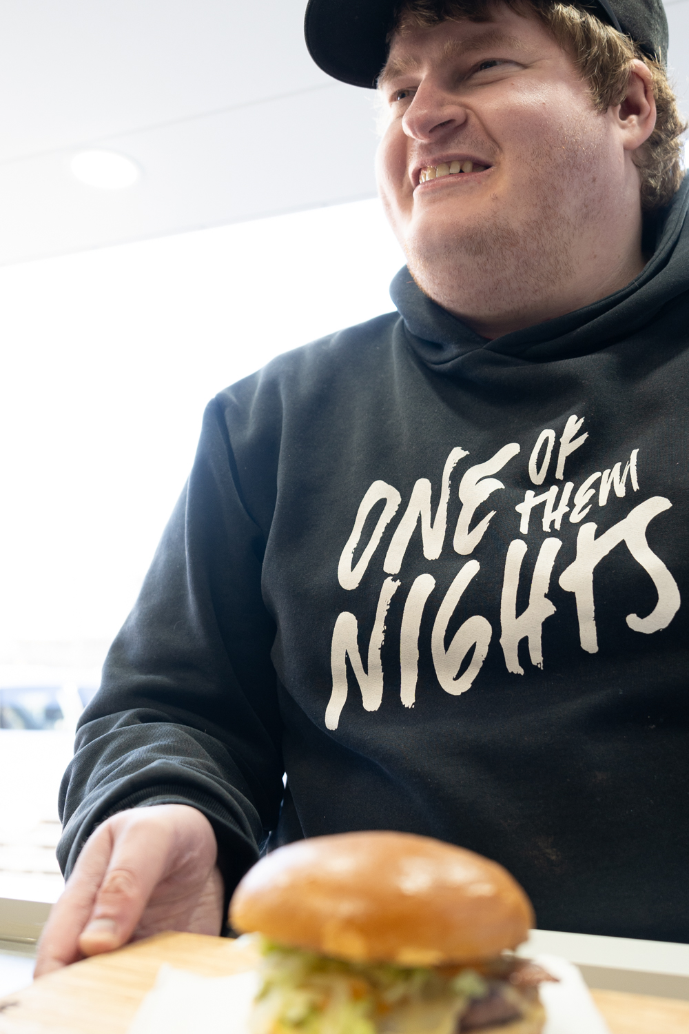 A man smiles and holds burger on a plate