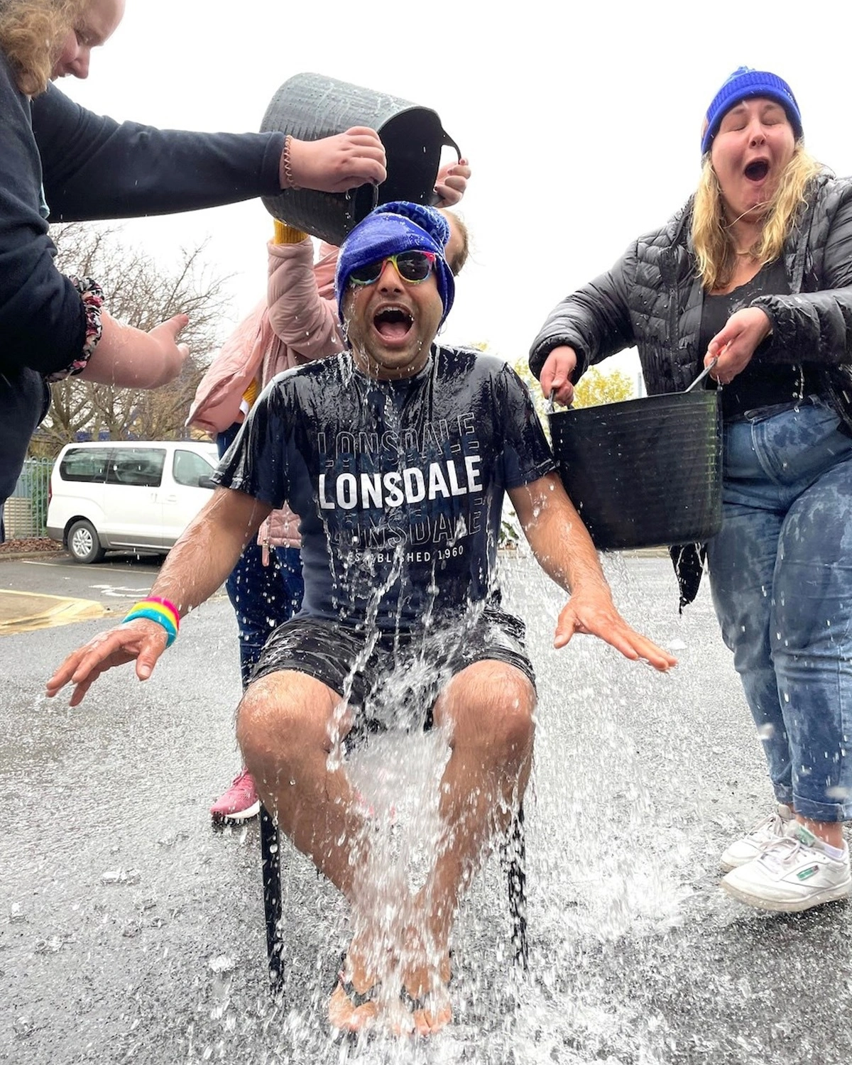A man smiles as he has a bucket of water poured over his head at fundraiser at NDIS registered disability provider Distinctive Options