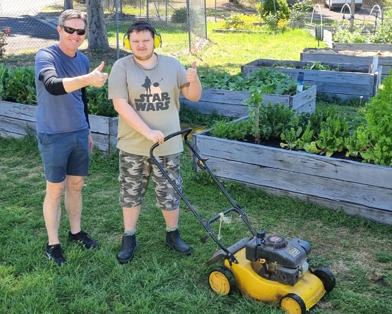 a young man and support worker mow the lawn at Distinctive Options Bendigo
