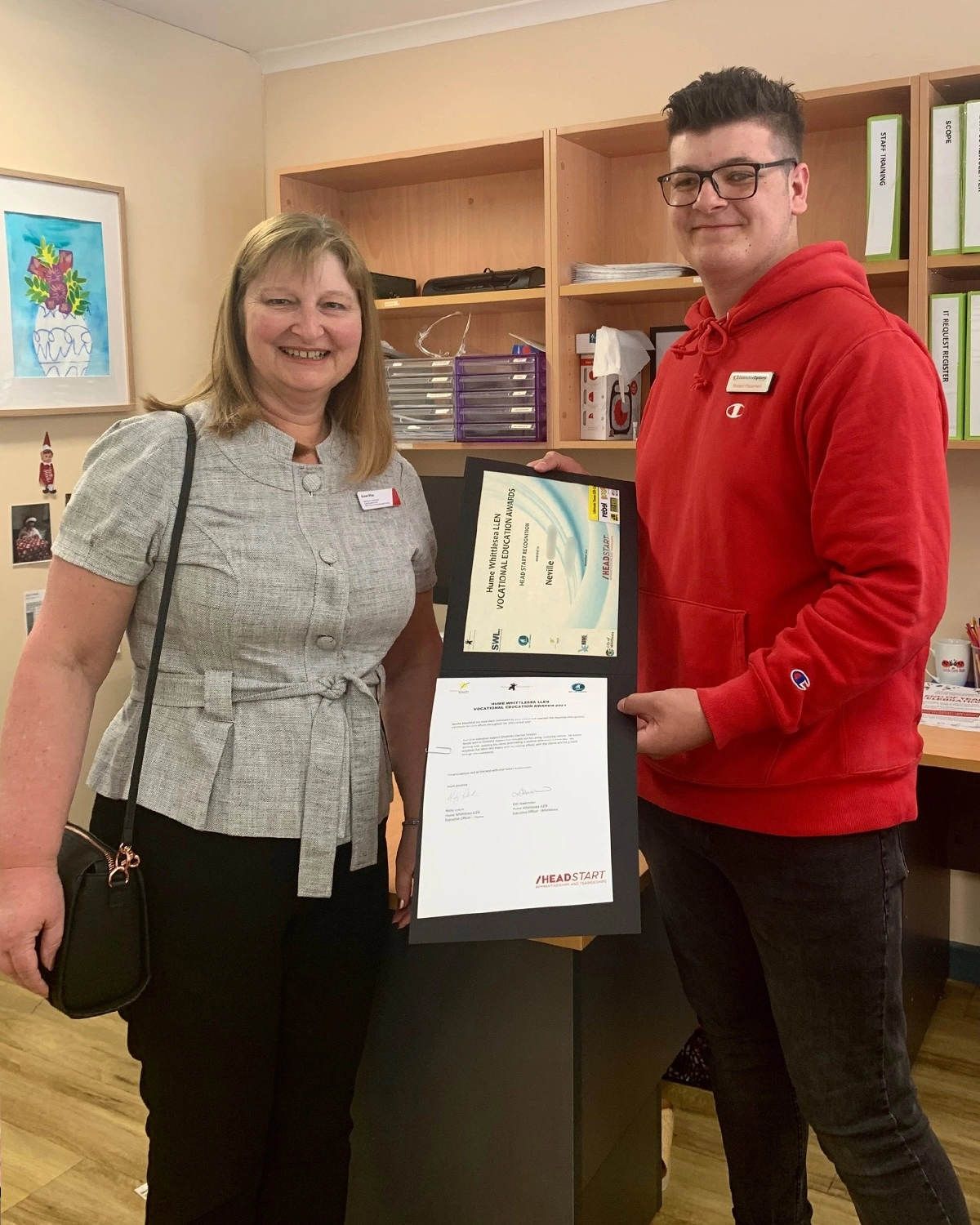 Two people hold volunteer certificates at NDIS registered disability support Distinctive Options