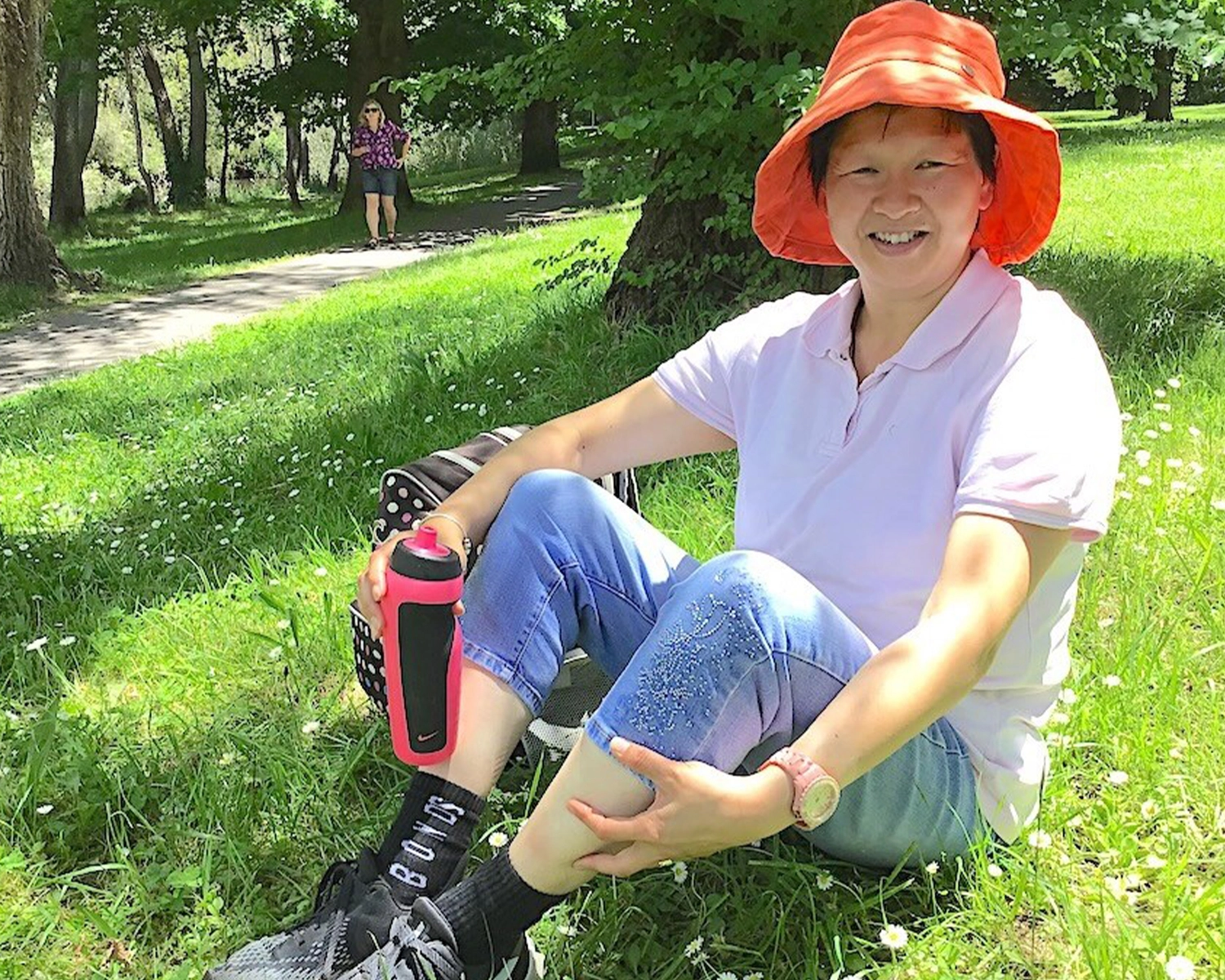 A woman sits on the grass in a park while at nature art and photography