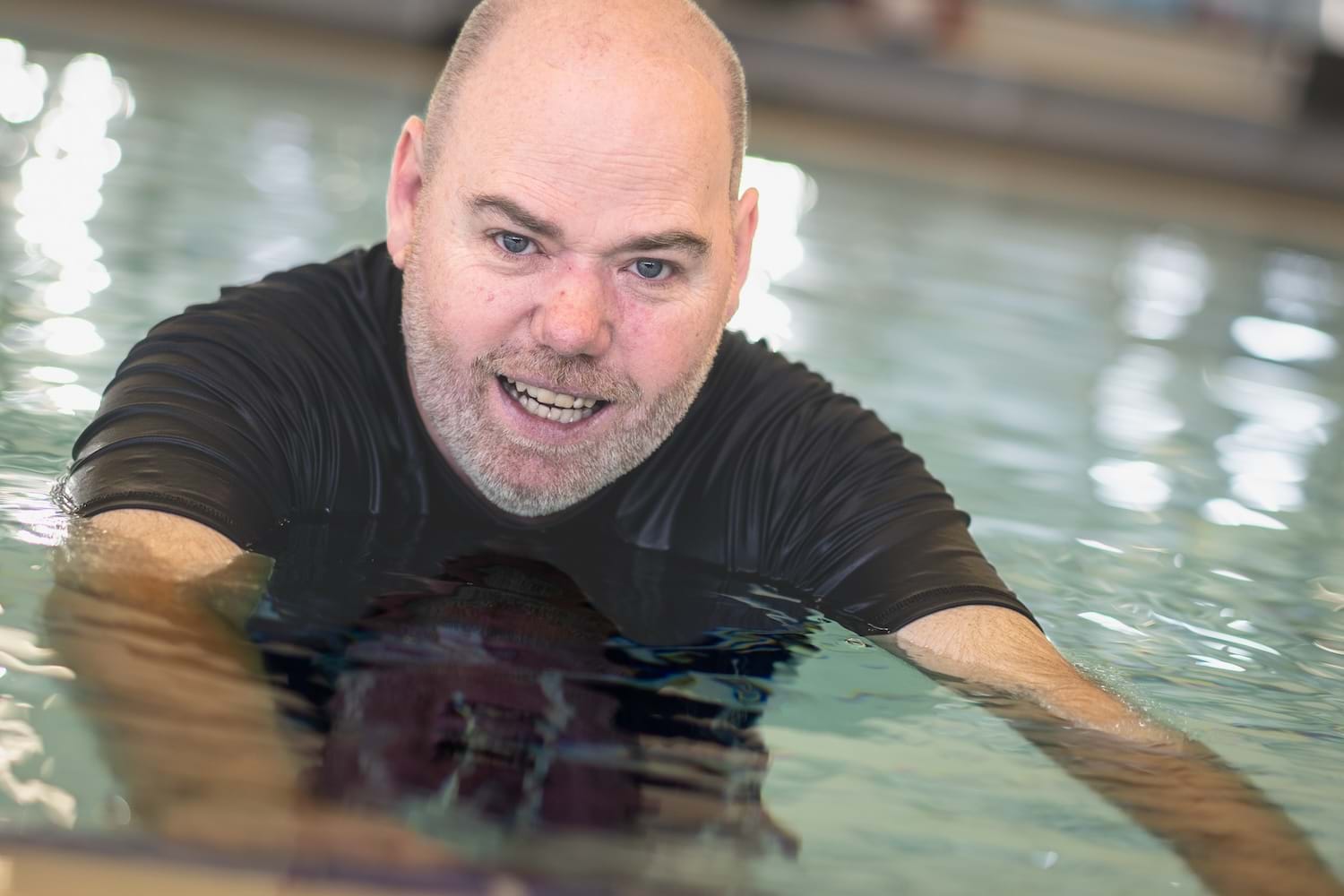 A man swims in a pool at NDIS registered disability service Distinctive Options Independent living supports