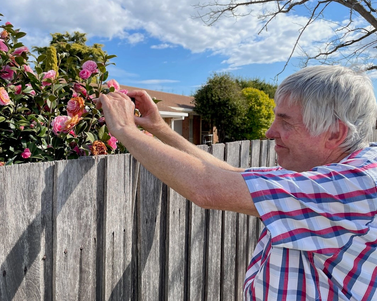 A man takes a photograph of a flower at Group Supports Photography program at Distinctive Options Noweyung