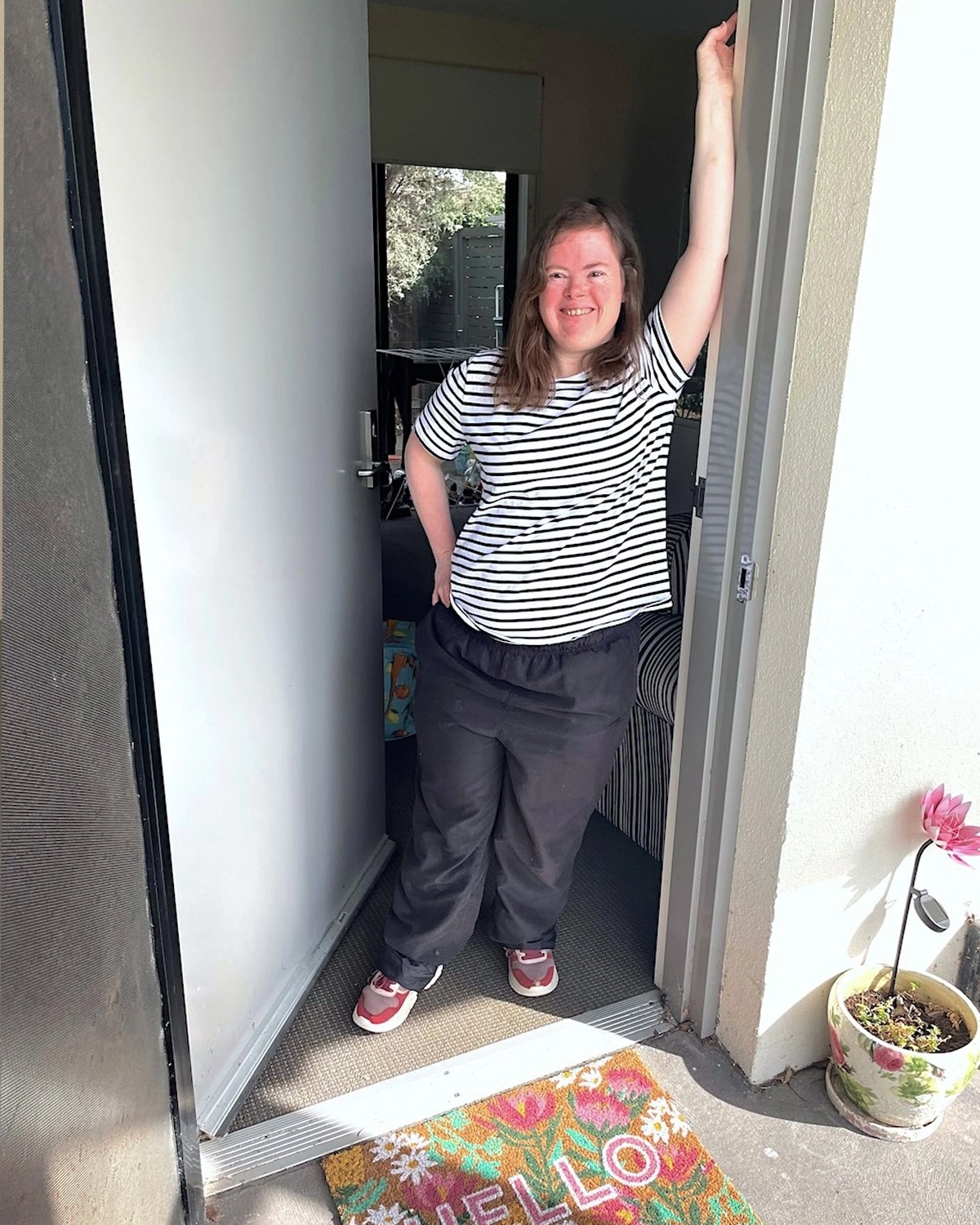 A woman stands by her front door at NDIS registered disability service Distinctive Options supported accommodation