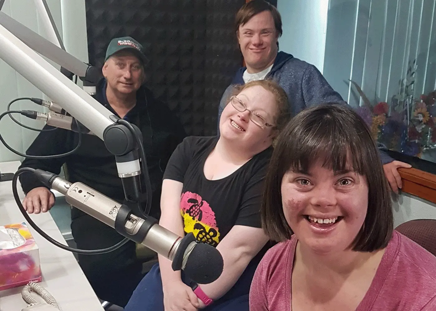 A group of people in a radio studio smile
