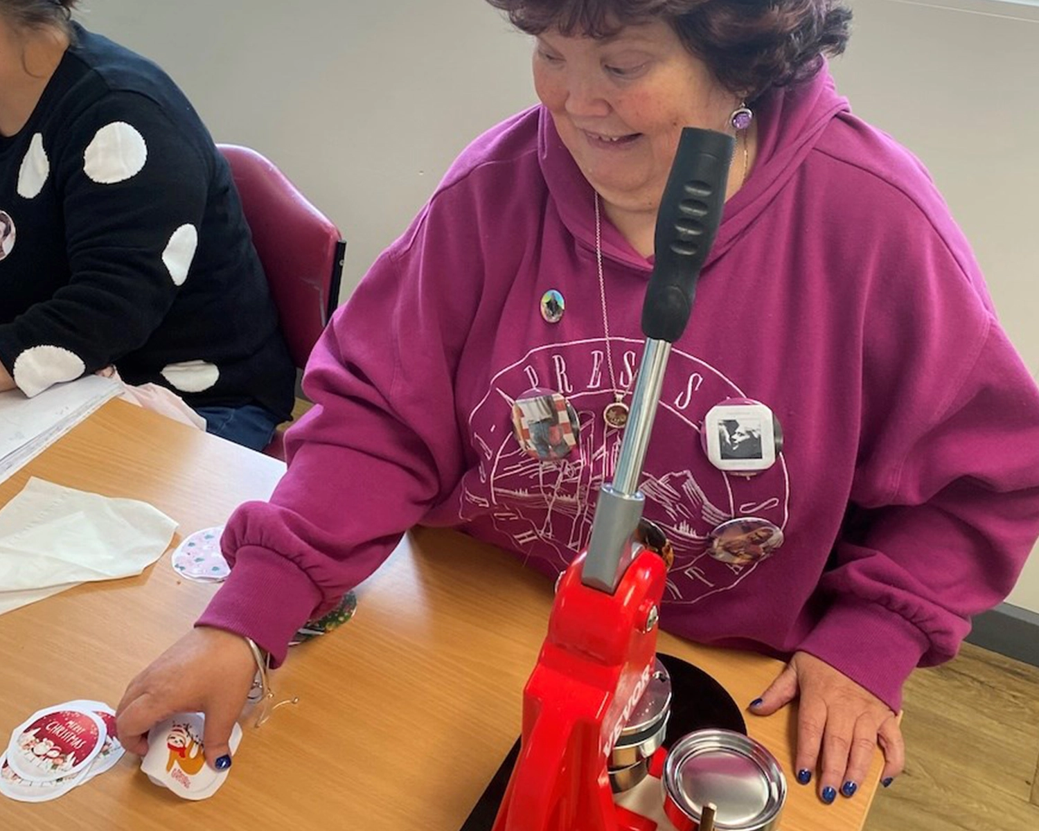 A woman makes badges at NDIS registered disability service Distinctive Options
