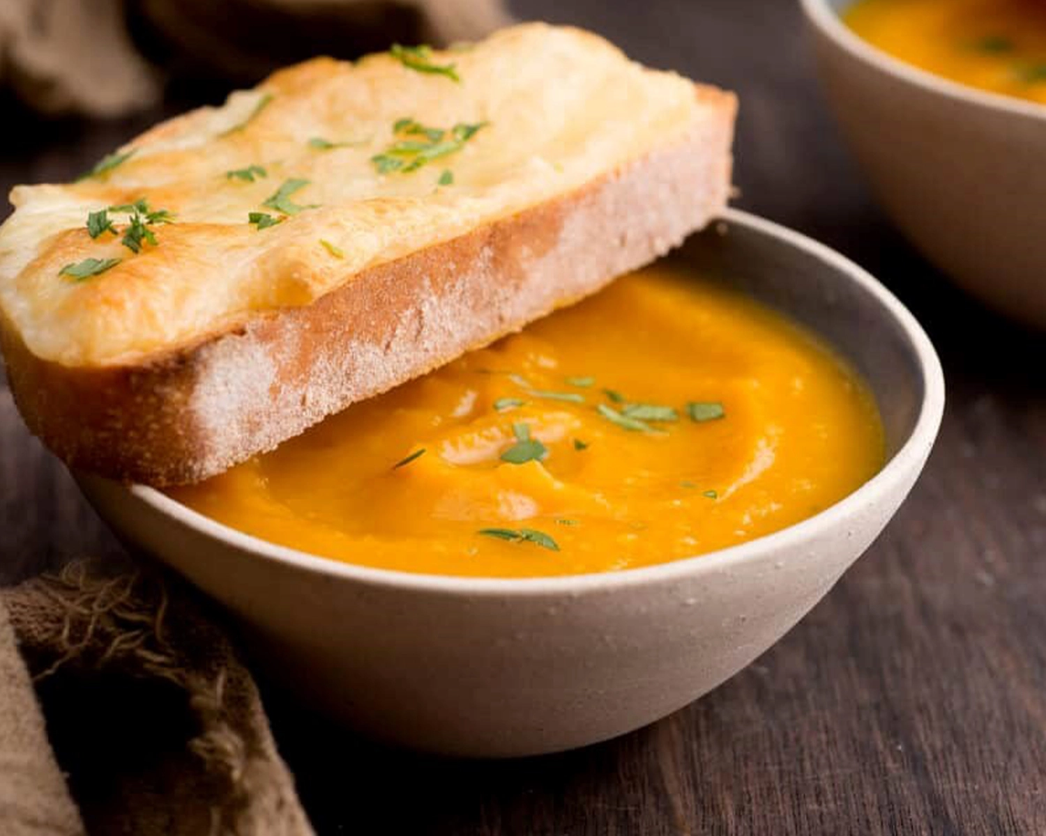 Bowl of pumpkin soup served with crusty toast