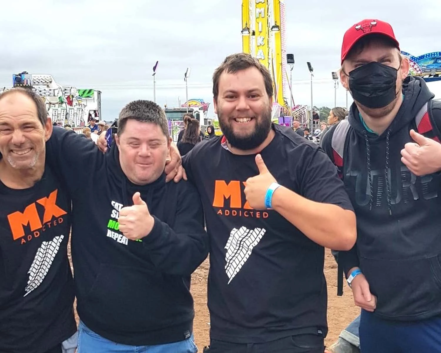 A group of men stand together at a fair, smiling with Group supports NDIS disability provider Distinctive Options