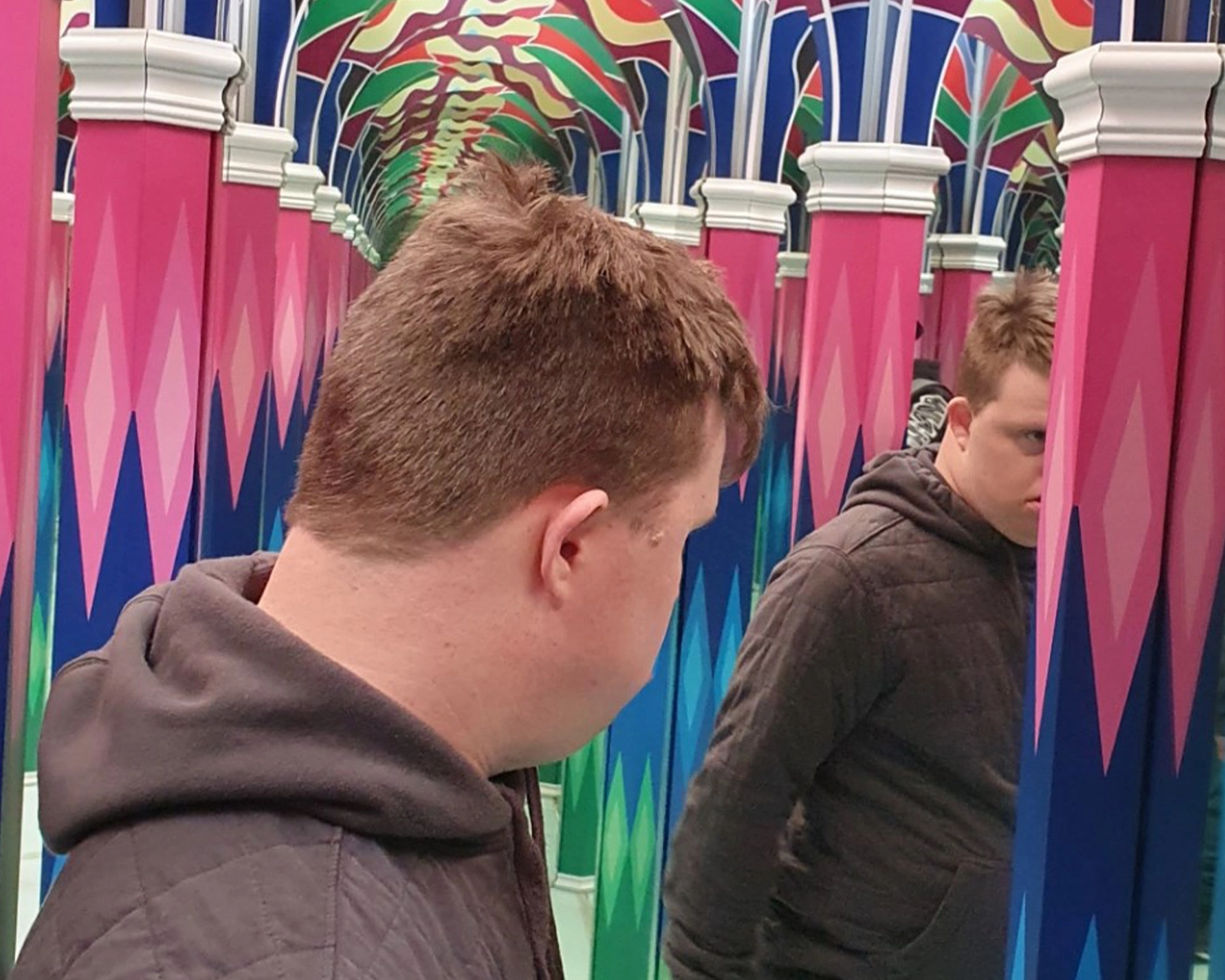 A young man looks at a series if mirrors inside a gallery at NDIS registered disability service Distinctive Options