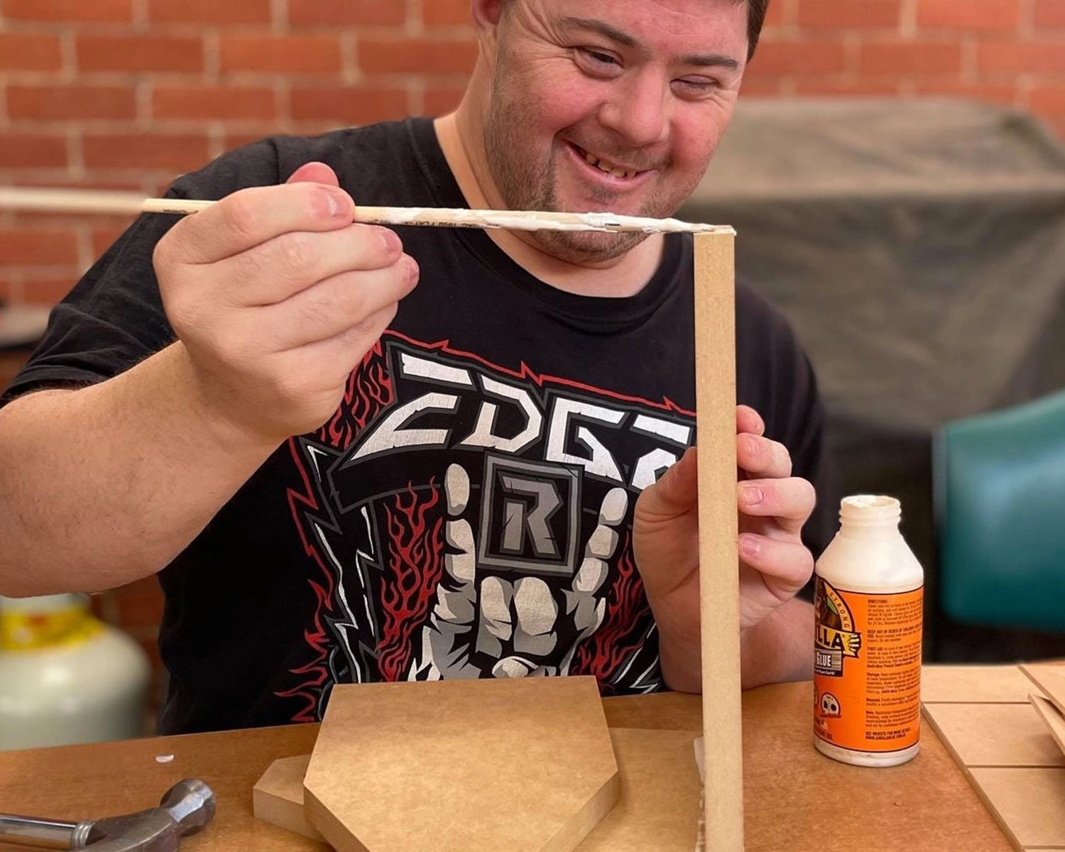 A man applies glue to a timber project at NDIS registered disability service Distinctive Options